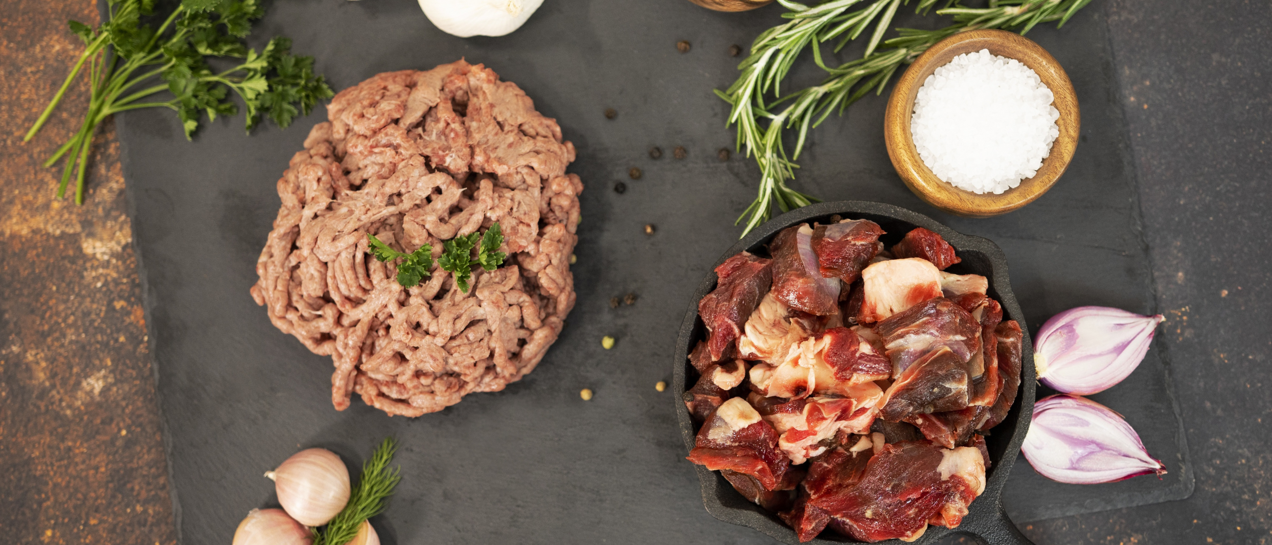 Ground and stew goat meat on a display board with garlic and variety of spices